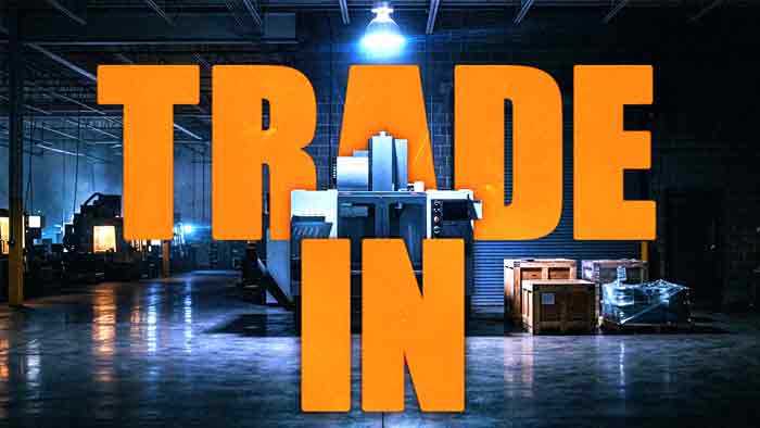 Trade In Your CNC Machine | Resell CNC Trade In over a spotlit CNC machining center staged for removal beside wooden crates in a dark machine shop