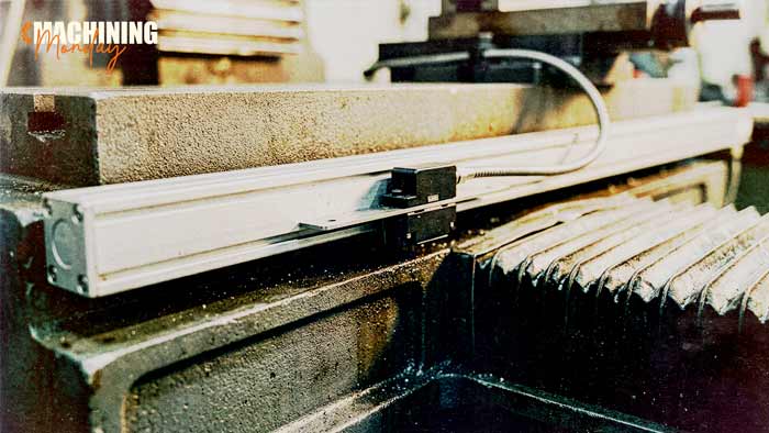 Sealed linear glass scale and scanning head mounted along a CNC machine axis for direct position feedback