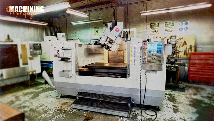 Gimbal-style 5-axis spindle head tilted over a flat clamped workpiece, as on the Haas VR-8