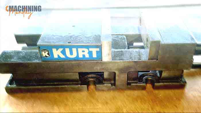 Kurt AngLock milling machine vise, side profile showing the blue Kurt badge, jaws, and hold-down base slots